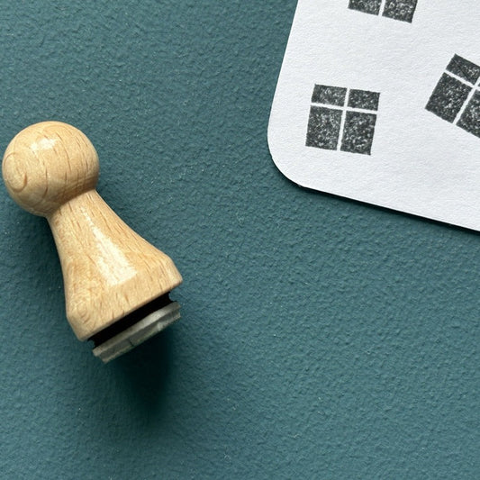 Mini-Stempel «Geschenk» von Mare di Maria – Holzstempel in Kegelform auf dunkelgrünem Grund, daneben schwarze Päckli-Abdrücke mit Kreuzband auf weisser Karte
