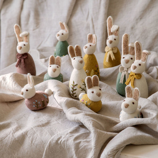 Filz-Hasen von Gry & Sif in einer Frühlingsszene – vorne links der sitzende Hase in Lavendel mit Blumenstickerei