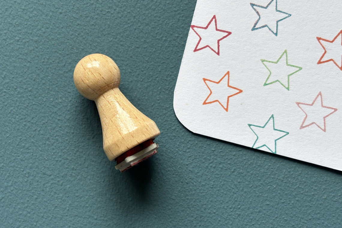 Mini-Stempel «Sternlinie» von Mare di Maria – Holzstempel neben bunten Stern-Konturen in Rot, Orange, Grün und Türkis auf weisser Karte