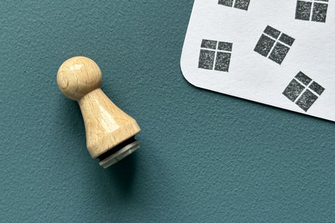 Mini-Stempel «Geschenk» von Mare di Maria – Holzstempel in Kegelform auf dunkelgrünem Grund, daneben schwarze Päckli-Abdrücke mit Kreuzband auf weisser Karte