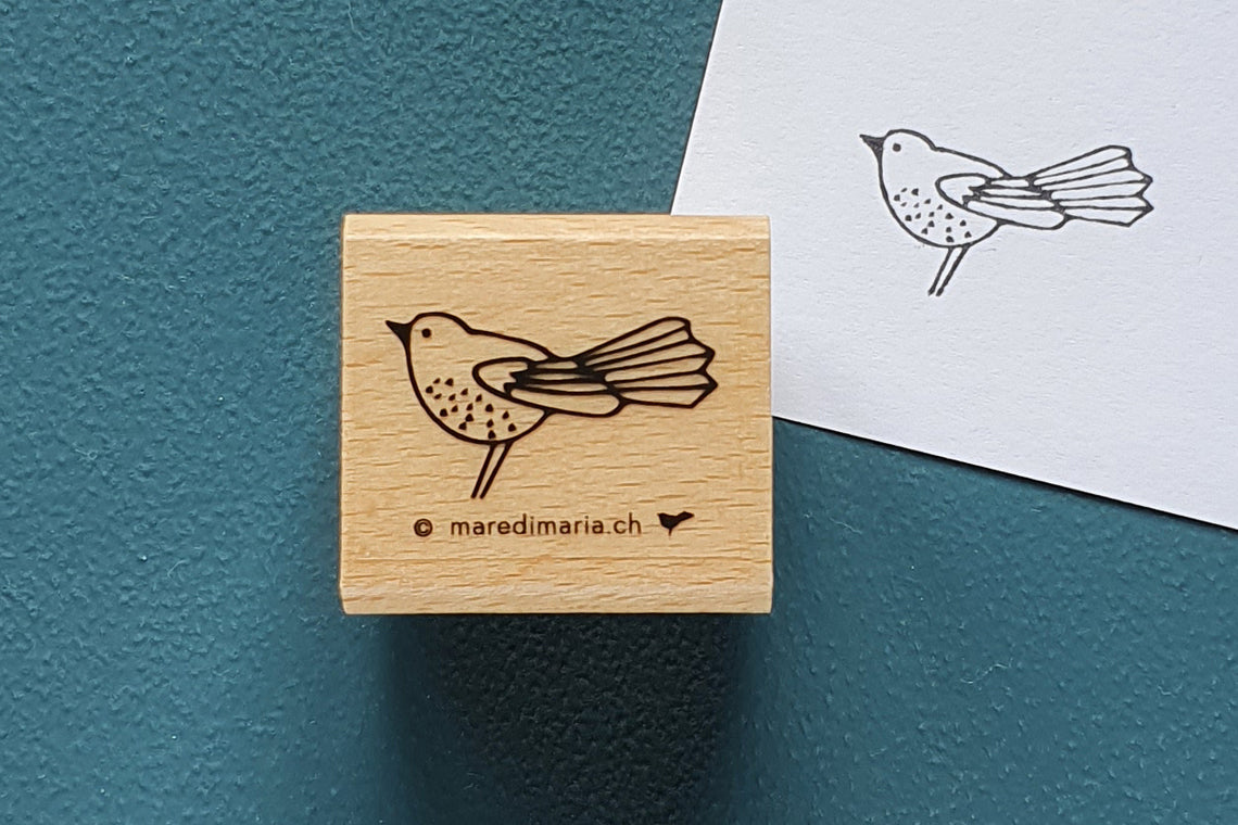 Holzstempel «Kleiner Vogel» von Mare di Maria – quadratischer Holzstempel mit Vogel mit Fächerschwanz auf dunkelgrünem Grund, daneben der schwarze Abdruck auf weissem Papier