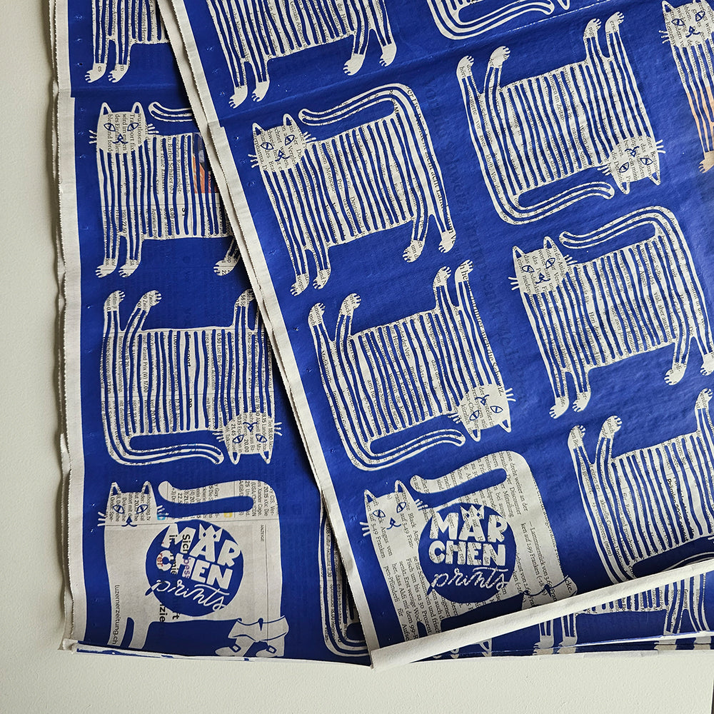 Wrapping paper «Puss in Boots» by Märchenprints laid out: striped cats, white on blue, screen-printed on newspaper