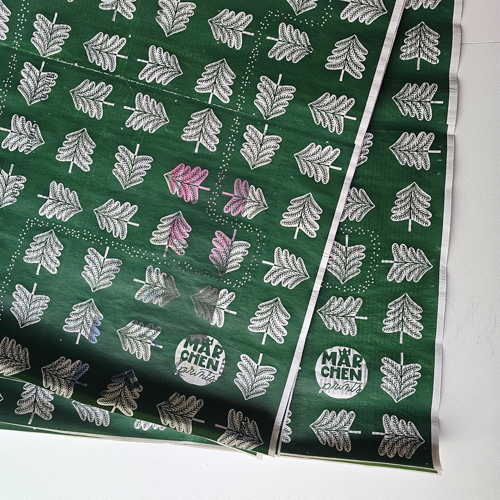 Wrapping paper «Hansel and Gretel» by Märchenprints laid out: fir trees, white on dark green, screen-printed on newspaper