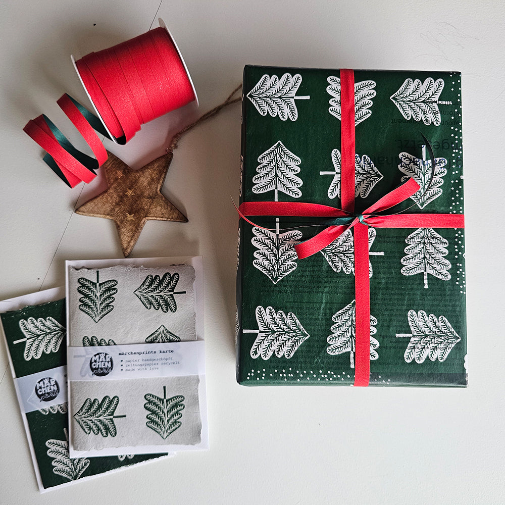 Present wrapped in «Hansel and Gretel» paper with a red ribbon, next to a card and a wooden star