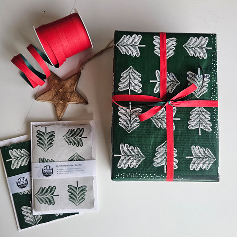 Present wrapped in «Hansel and Gretel» paper with a red ribbon, next to a card and a wooden star