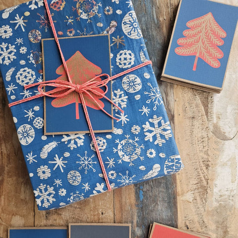 Present in blue snowflake paper with a «Fir Tree» card and red string, more cards alongside
