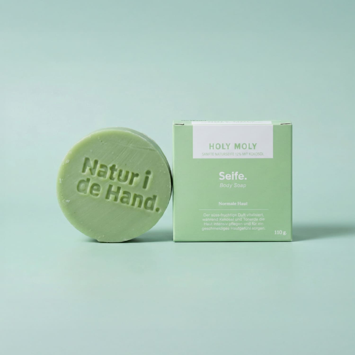 Savon naturel Holy Moly de Natur i de Hand – savon rond vert avec le logo Natur i de Hand en relief, à côté de sa boîte vert clair