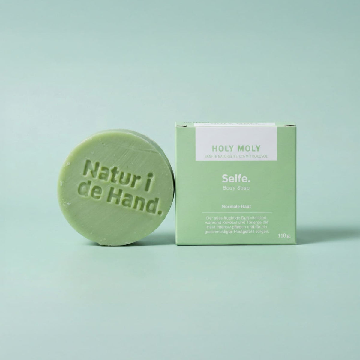 Savon naturel Holy Moly de Natur i de Hand – savon rond vert avec le logo Natur i de Hand en relief, à côté de sa boîte vert clair