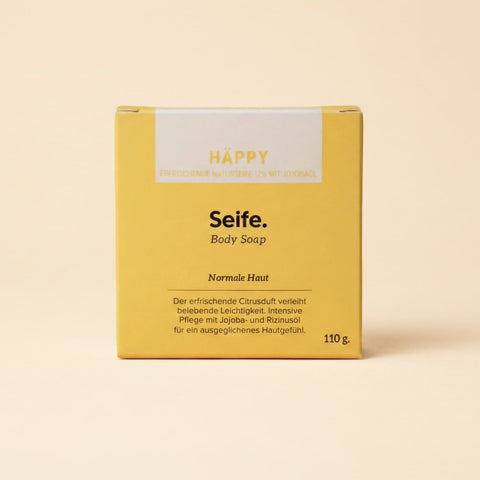 Naturseife Häppy von Natur i de Hand – gelbe Kartonschachtel mit Aufschrift «Häppy – Seife – Body Soap», 110 g