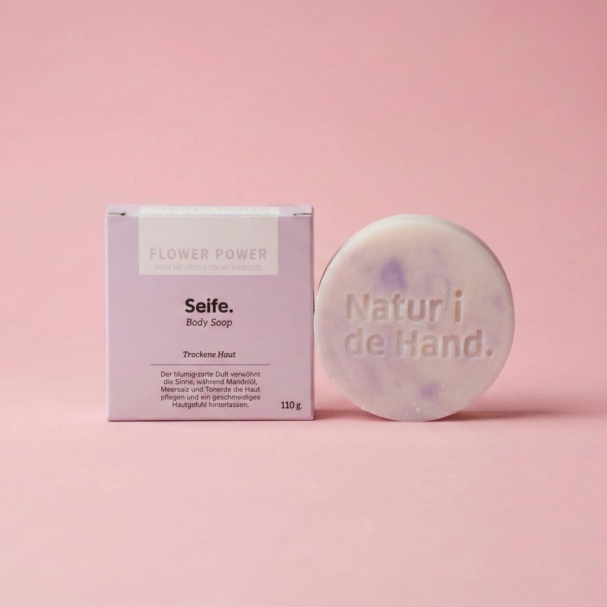 Savon naturel Flower Power de Natur i de Hand – savon rond marbré blanc et lilas avec le logo Natur i de Hand en relief, à côté de sa boîte lilas