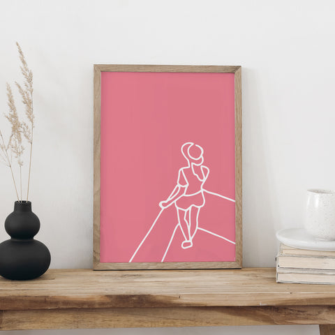 Plakat «Aussicht» im hellen Holzrahmen auf einem Holztisch an weisser Wand, daneben eine schwarze Vase mit Trockengräsern und ein Bücherstapel mit Tasse