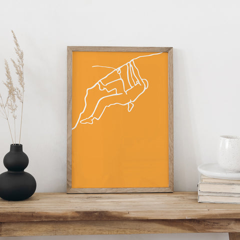 NaniManu Plakat «Klettern» im Holzrahmen auf einer Holzbank an weisser Wand, daneben schwarze Vase mit Trockengräsern und ein Bücherstapel mit Tasse