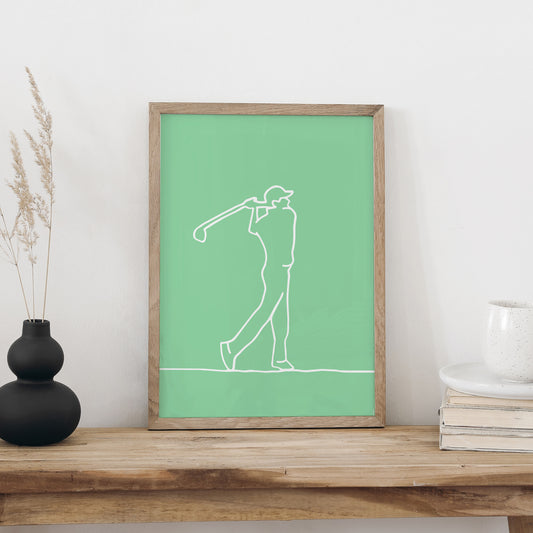 Plakat «Golf» im Holzrahmen auf einer Holzbank an weisser Wand, daneben eine schwarze Vase mit Trockengräsern und ein Bücherstapel mit Tasse
