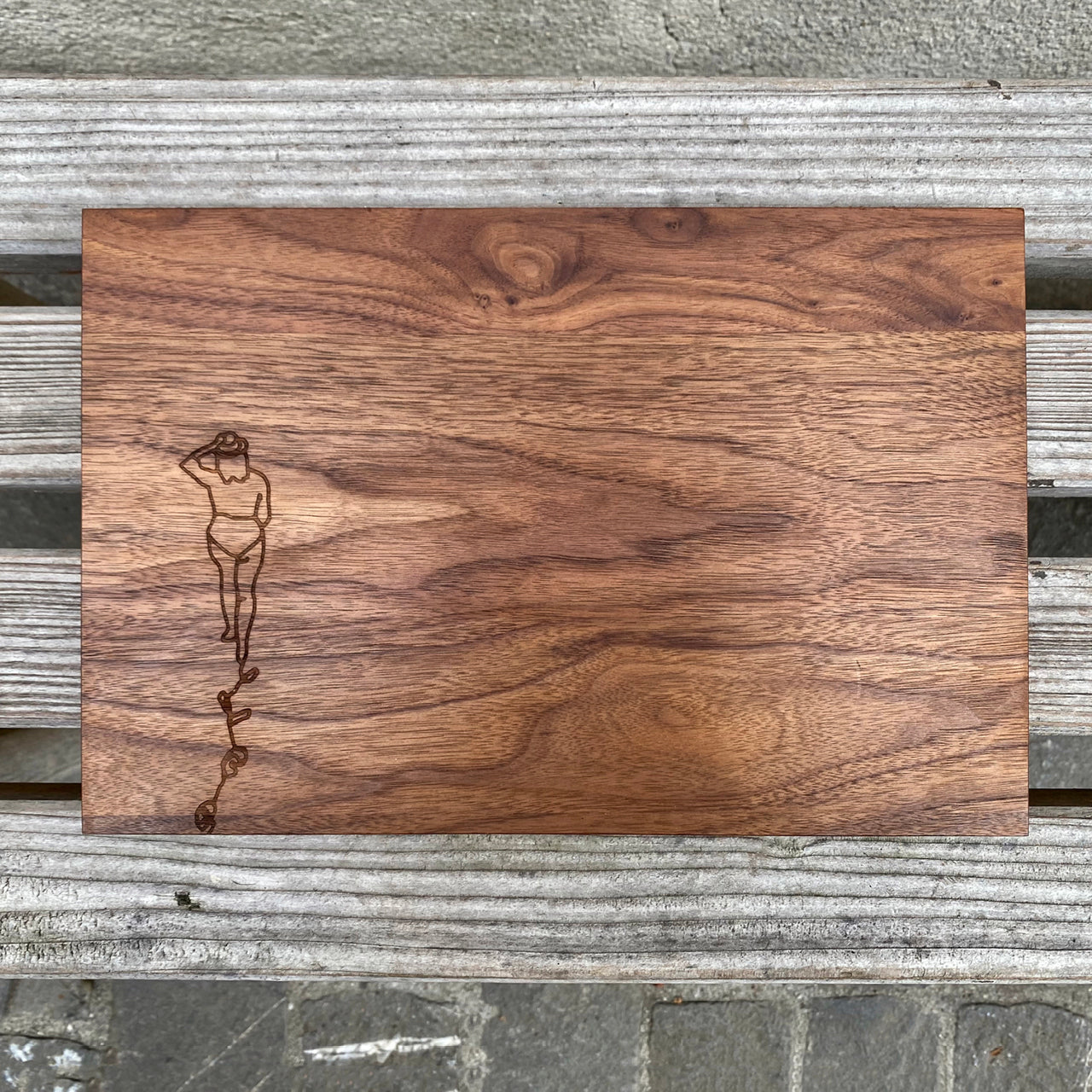 Schneidebrett Nussbaum – Stimmungsbild draussen, dunkles Holz auf grauer Holzbank, Motiv von oben