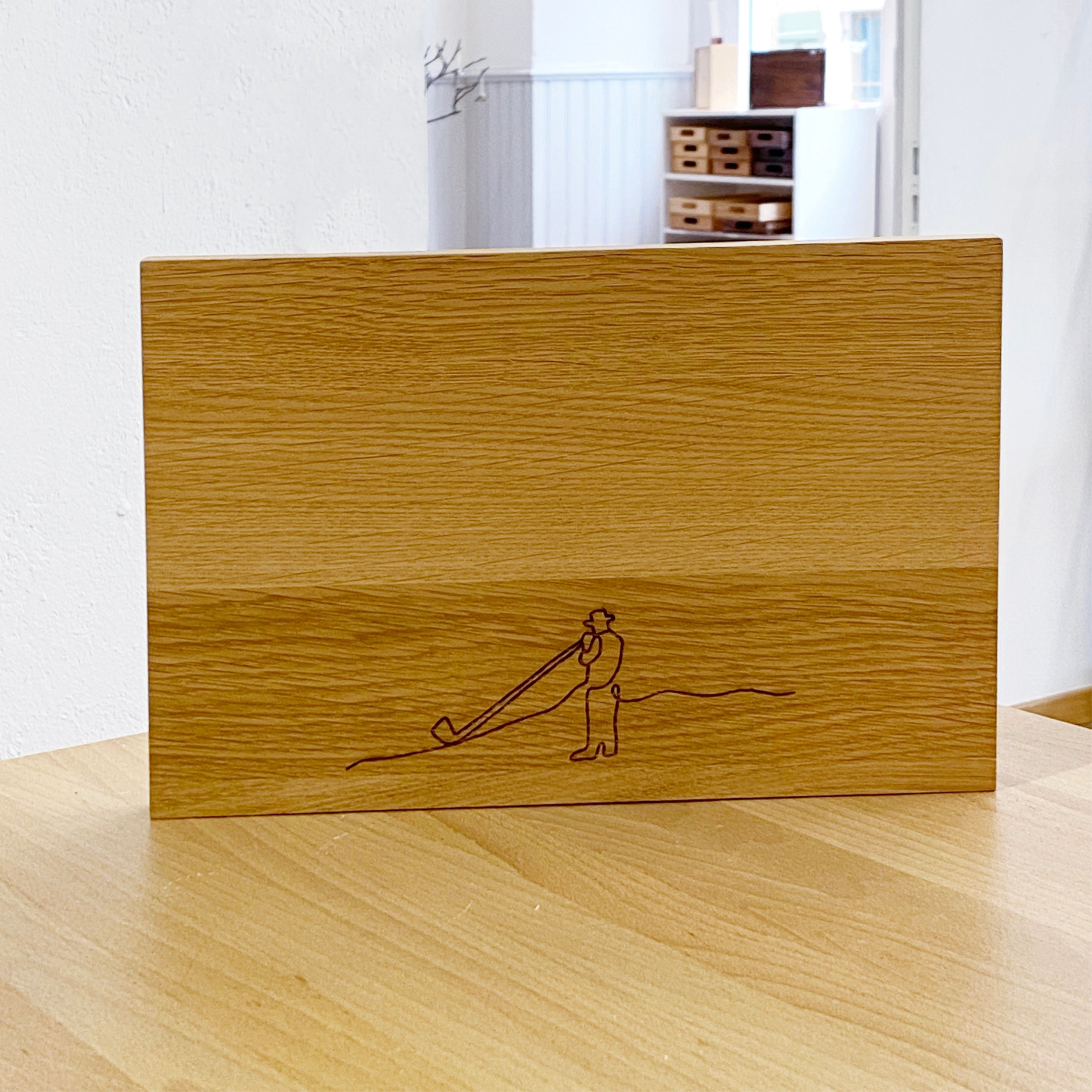 Schneidebrett Eiche Grösse S steht aufrecht auf einem Holztisch, im Hintergrund ein Regal