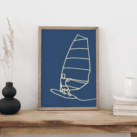 Windsurfen-Plakat im Holzrahmen auf einer Holzbank, daneben eine schwarze Vase mit Trockengräsern und eine weisse Tasse auf Büchern