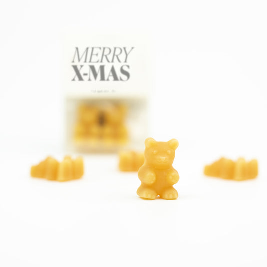 Einzelner oranger Tee-Bär von TaTeeTaTa im Vordergrund, dahinter unscharf das Tütchen «Merry X-Mas»