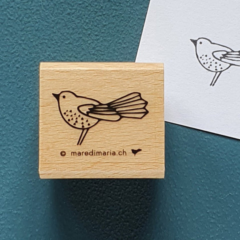 Holzstempel «Kleiner Vogel» von Mare di Maria – quadratischer Holzstempel mit Vogel mit Fächerschwanz auf dunkelgrünem Grund, daneben der schwarze Abdruck auf weissem Papier